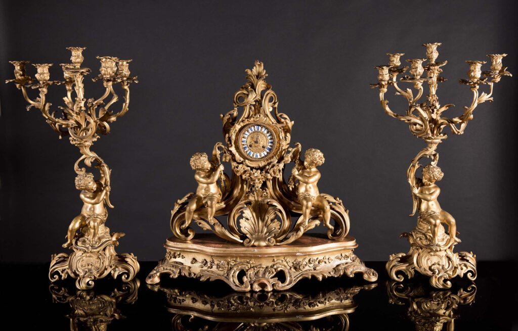 Importante trittico in bronzo dorato composto da orologio e due candelabri.
