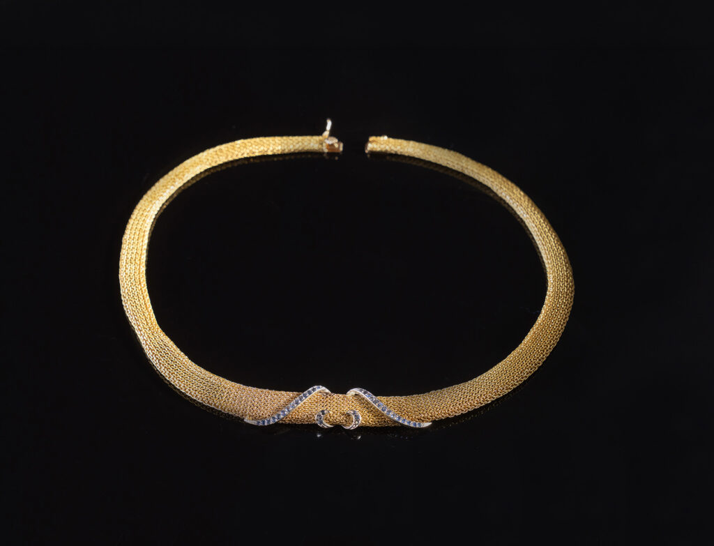 Collier in oro giallo 18 kt a maglia tessuto con elemento centrale in oro bianco impreziosito da zaffiri.