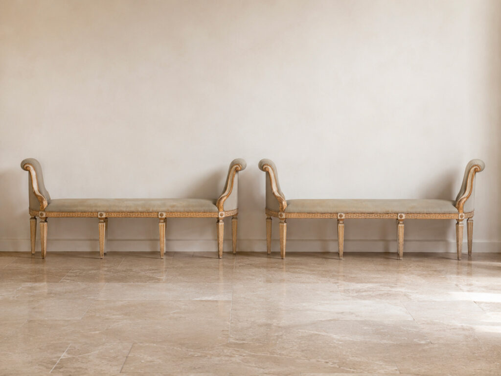 Coppia di panchetti a muro Emilia-Lombardia della fine del XVIII secolo in legno intagliato, laccato e dorato con motivo a greca e sostegni scanalati. Trattati da Gregory's Casa d'Aste Bologna, prima casa d'aste di Bologna dal 2013.