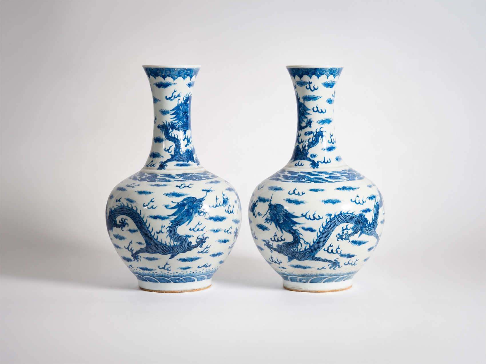 Pair of Chinese blue and white porcelain vases decorated with imperial dragons among clouds, Qing dynasty, early 20th century.