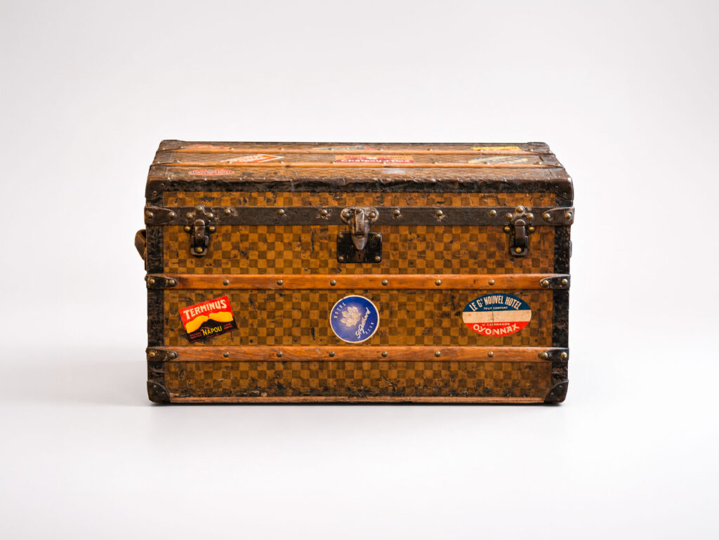 Baule da viaggio Louis Vuitton rivestito in tela di iuta con finiture metalliche e adesivi di viaggio originali.