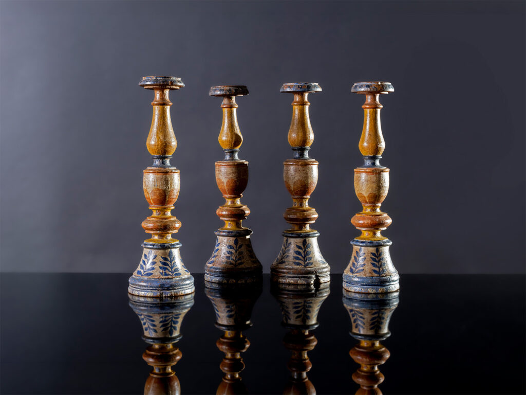 Quattro candelieri in legno tornito e laccato in policromia con decorazione a palmette blu, Marche, XVIII secolo.