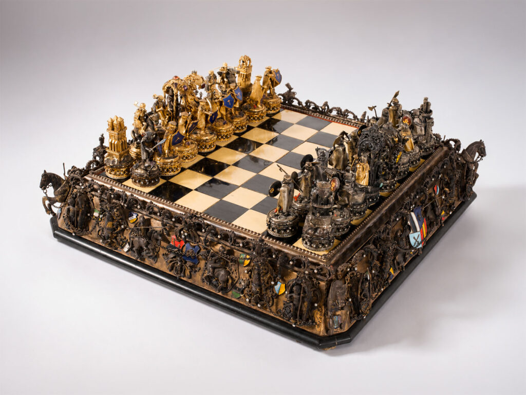 Importante scacchiera Austro-Ungarica in argento dorato con set di scacchi in argento, smalti e pietre dure, XX secolo.