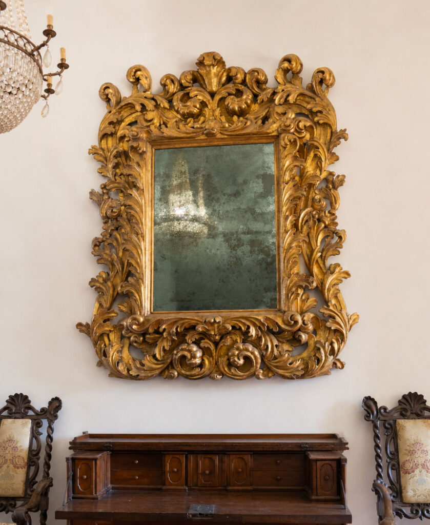 Specchiera monumentale Emilia-Toscana della prima metà del XVII secolo in legno intagliato e dorato. Opera trattata da Gregory's Casa d'Aste Bologna, casa d'aste dal 2013 specializzata in arte antica e arredi storici.