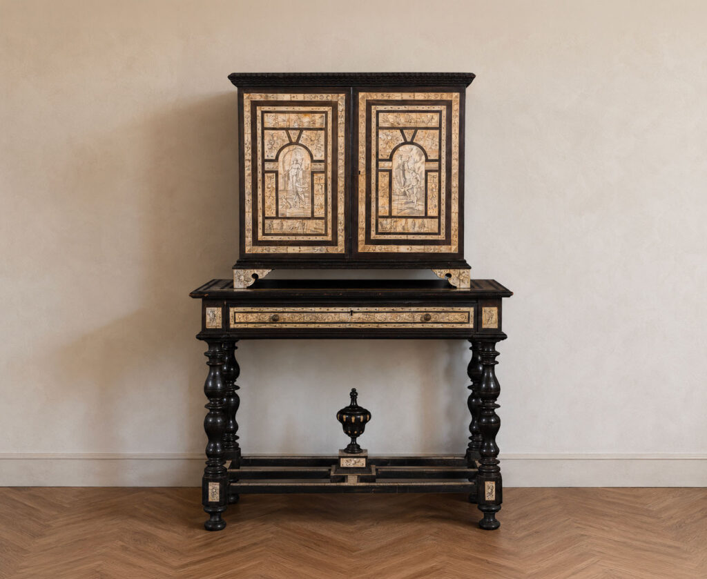 Importante stipo monetiere lombardo del XVIII secolo lastronato in ebano e avorio con tavolo d'appoggio originale, decorato con scene mitologiche e scene di vita quotidiana. Trattato da Gregory's Casa d'Aste Bologna, prima casa d'aste di Bologna dal 2013.