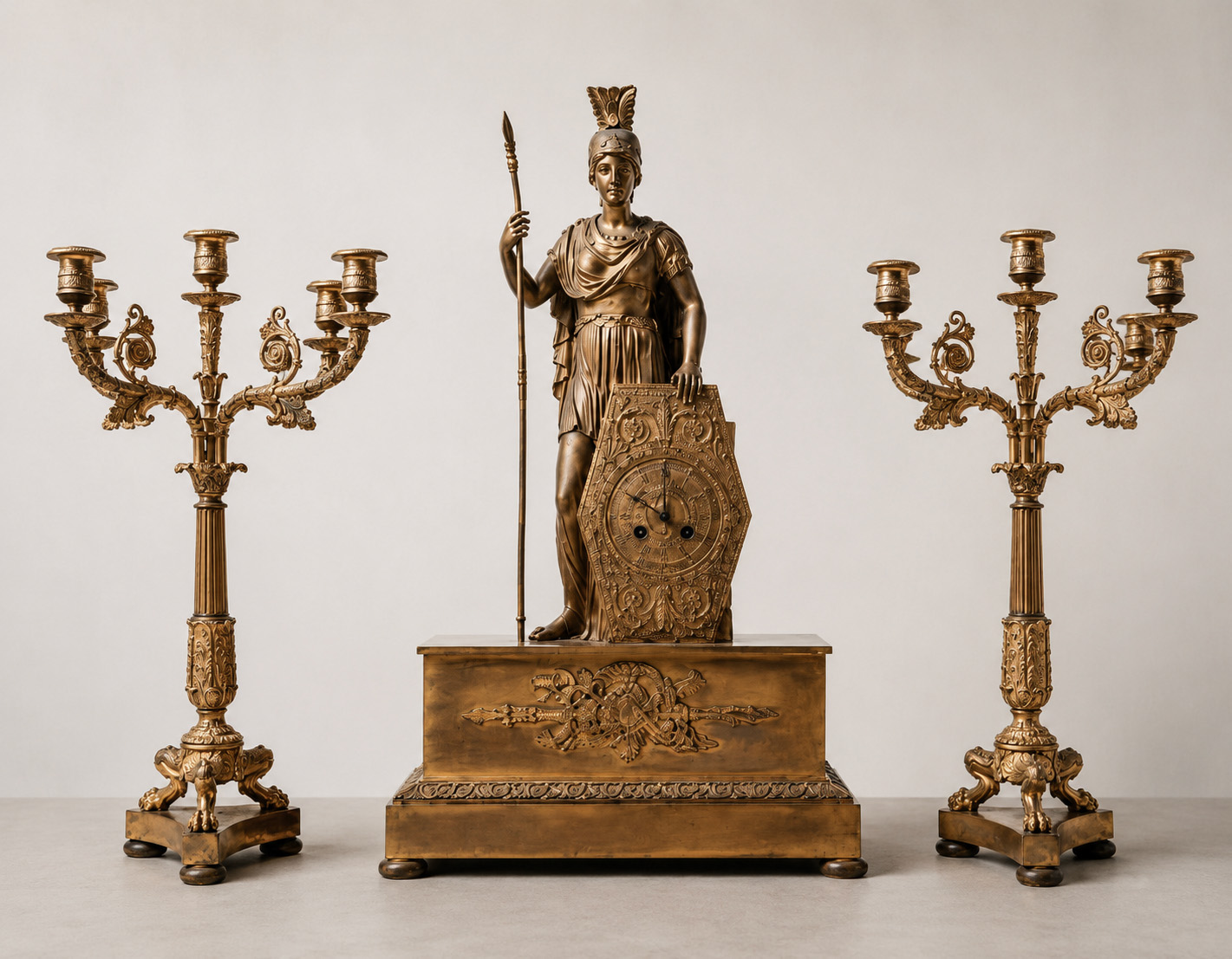 Trittico francese del XIX secolo in bronzo dorato composto da orologio con Minerva e coppia di candelabri a cinque fiamme.