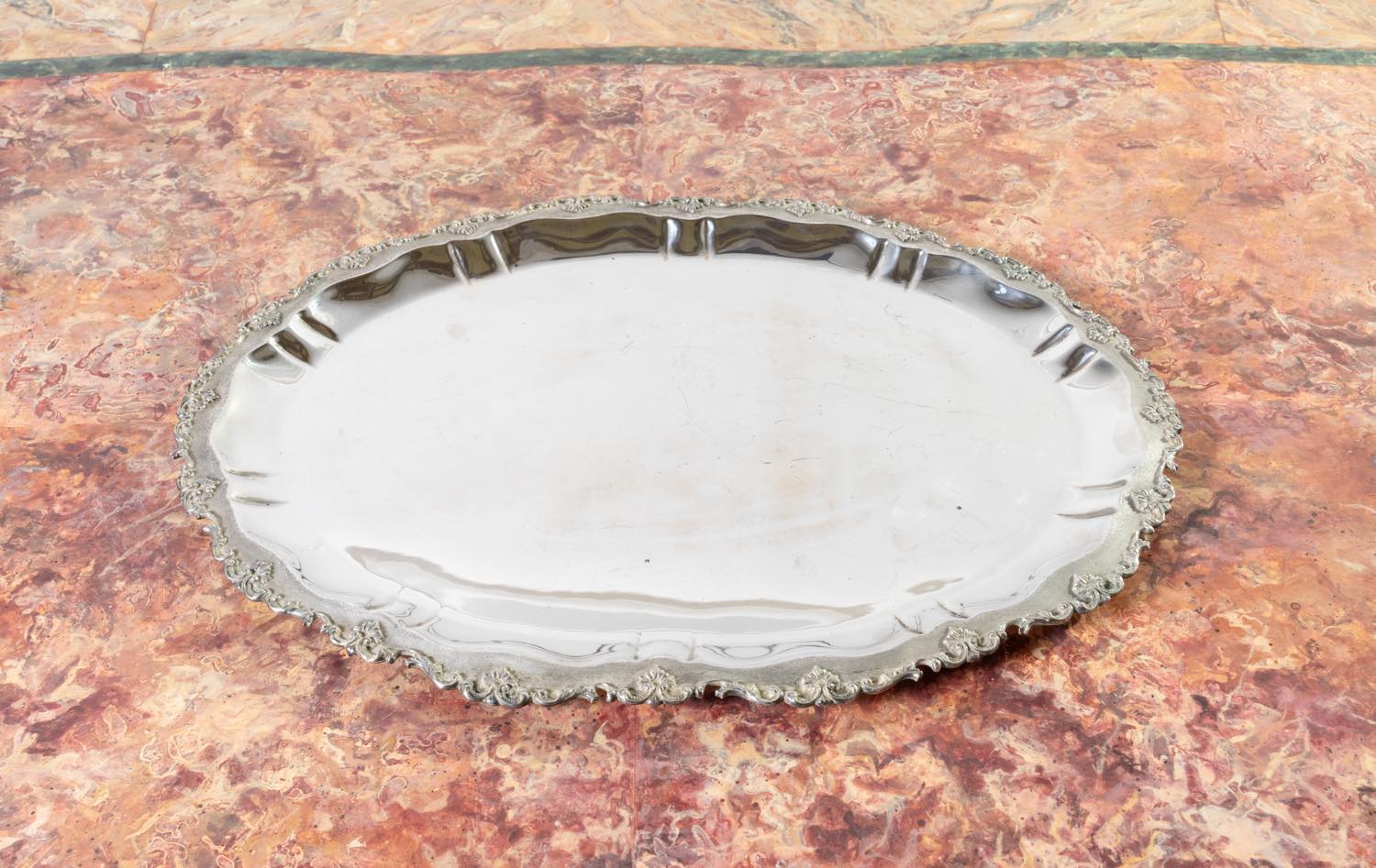 Vassoio da portata in argento 800 di Veralda Argentiere, Vercelli, XX secolo, con superficie specchiante e bordo mistilineo decorato a volute e palmette.