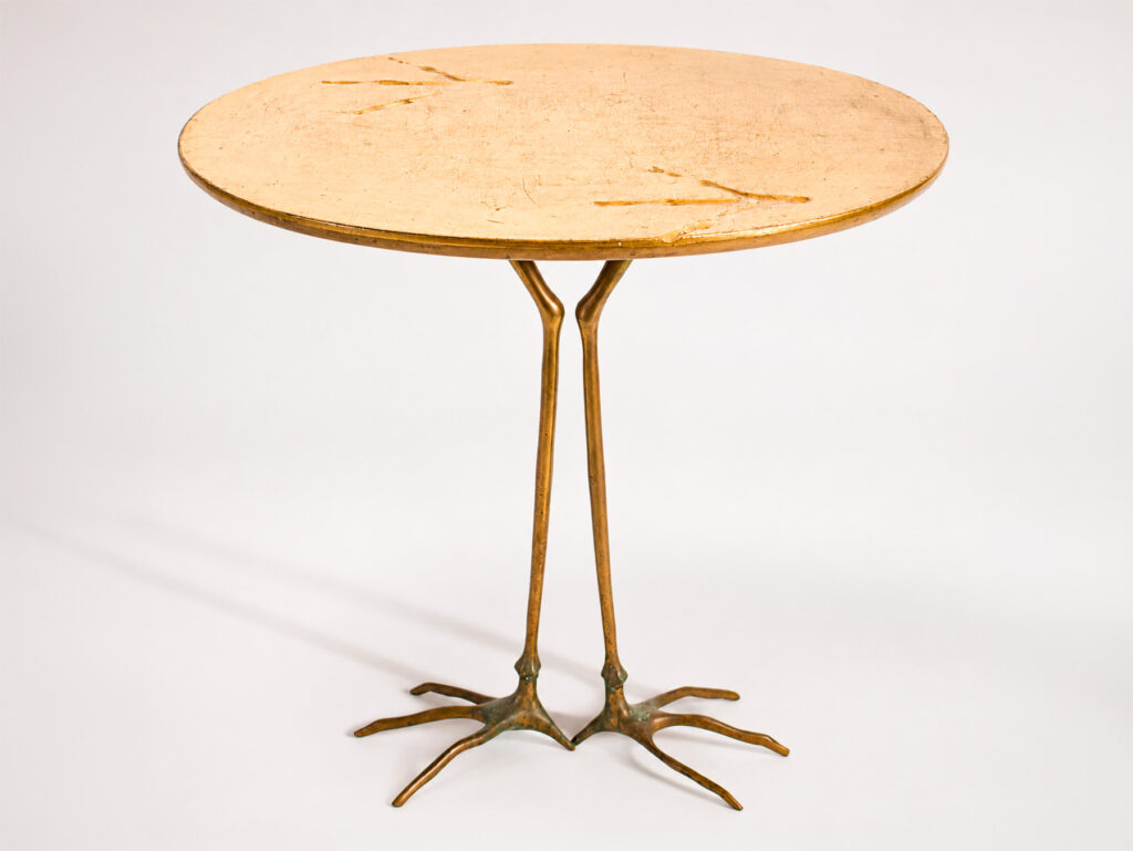 Meret Oppenheim per Simon Gavina, tavolo "Traccia" con piano rivestito in foglia d'oro zecchino e base in bronzo fuso, anni Ottanta.